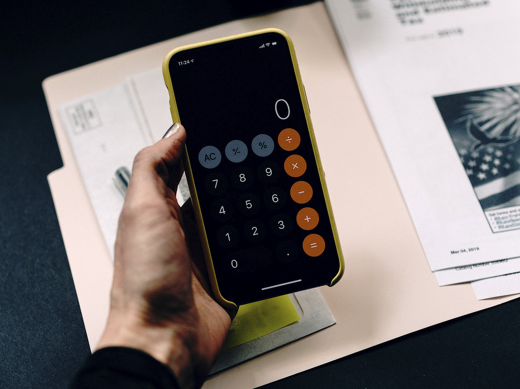 Ein Handy mit einer Taschenrechner-App, das über einer Abrechnung gehalten wird