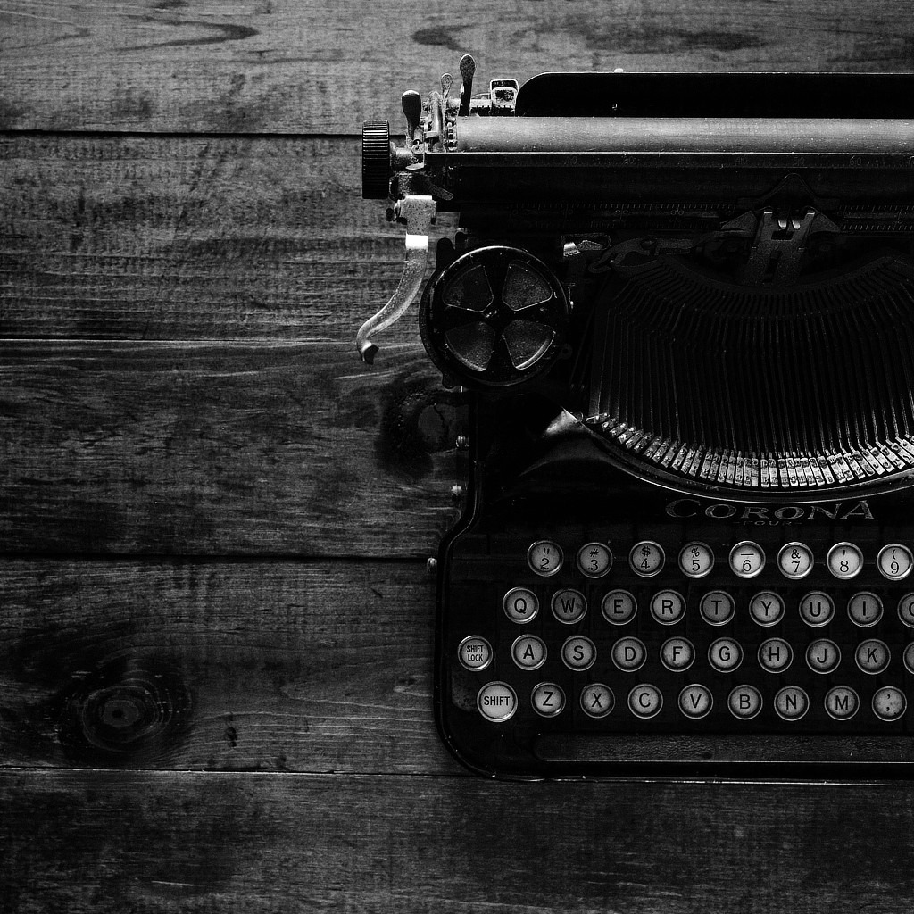 Ein schwarz-weiß Foto einer alten Schreibmaschine auf einem rustikalen Tisch