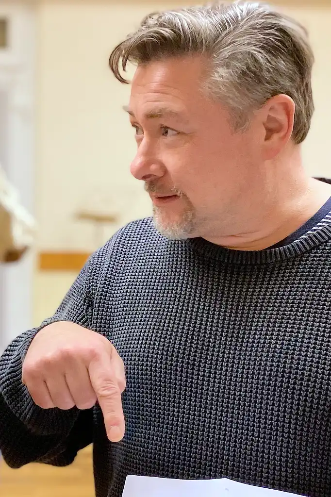 Mann in erklärender Pose zeigt mit dem Finger zu Boden
